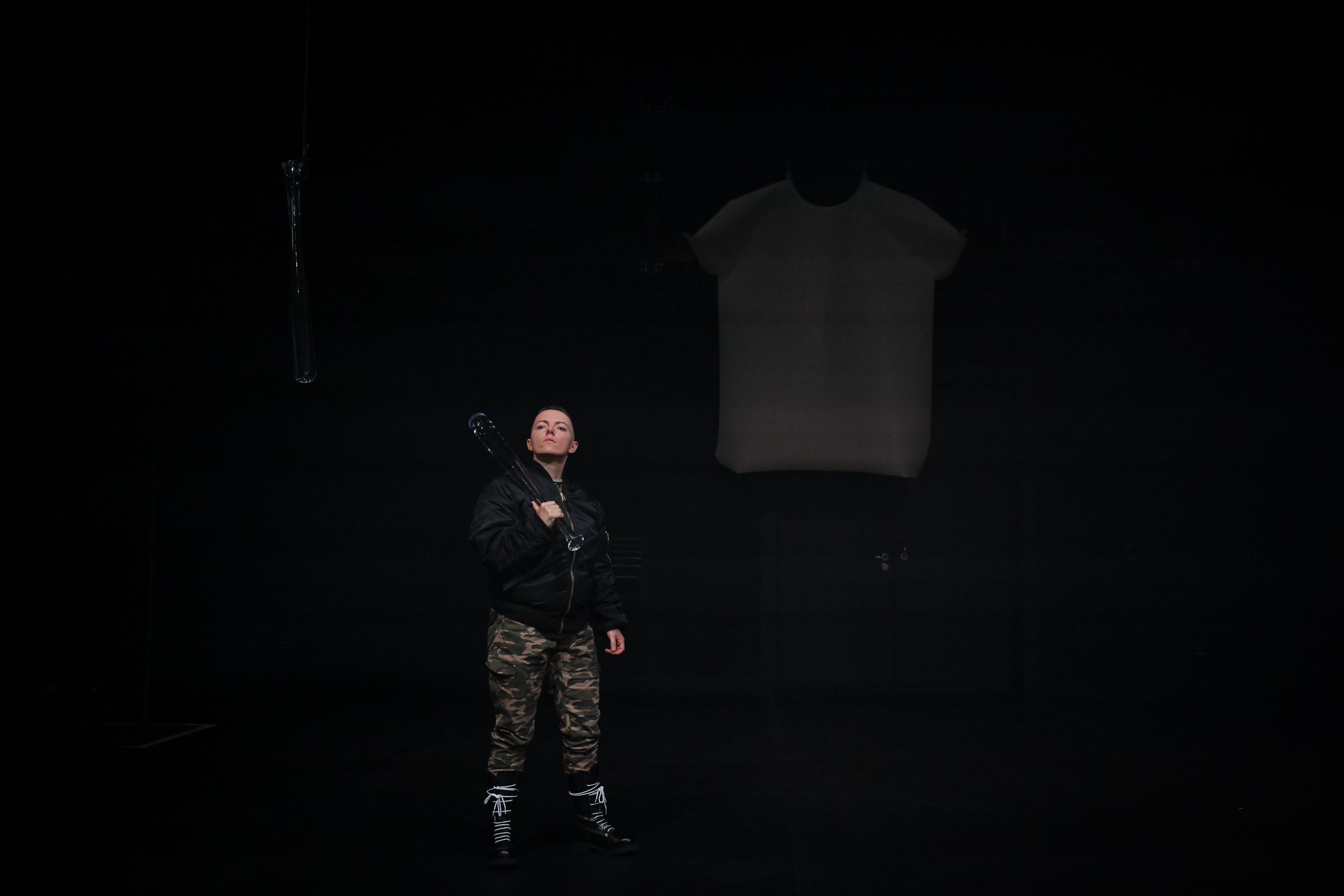 Mike steht in der Bühnemitte in schwarzer Bomberjacke, mit gläsernem Baseballschläger über der Schulter.